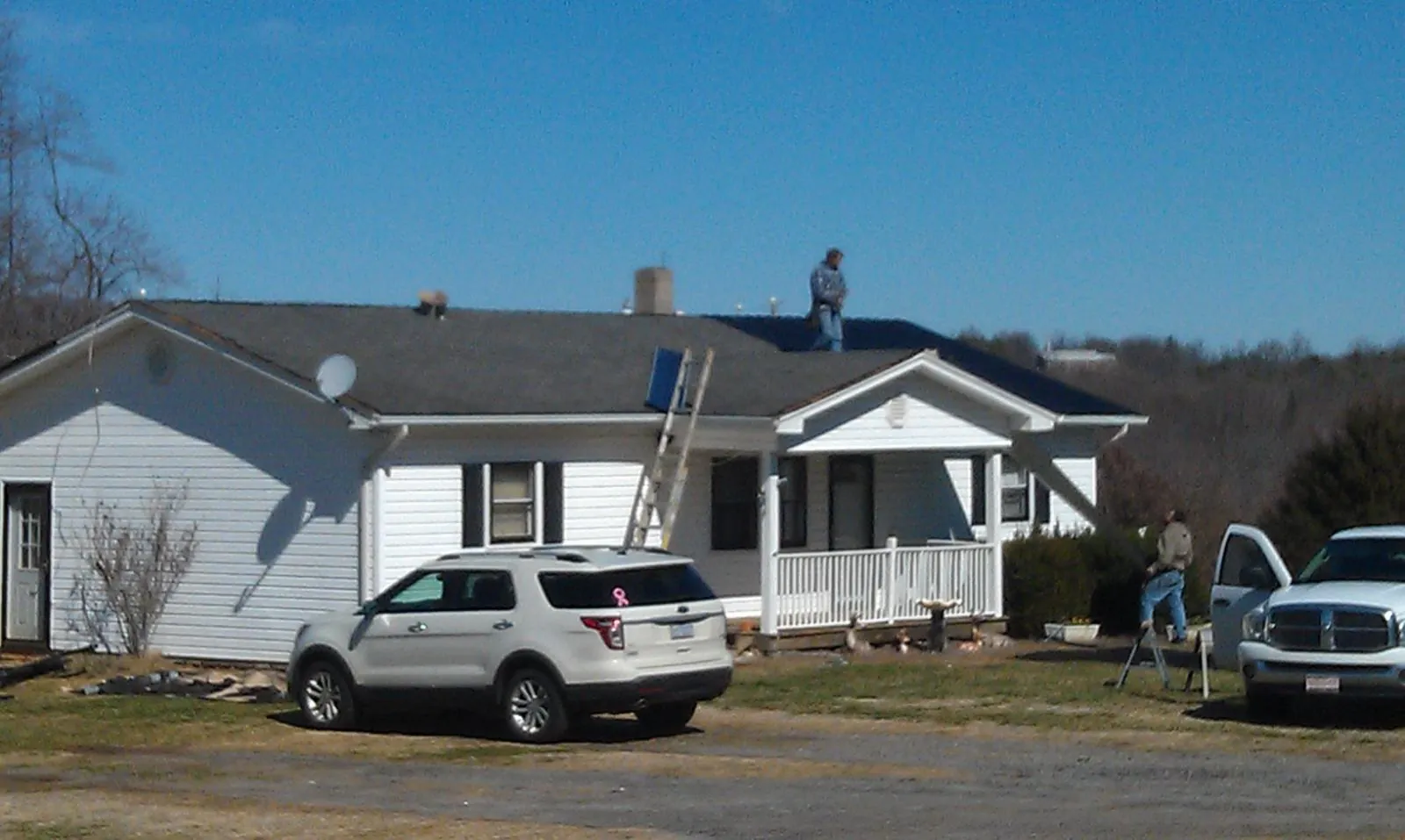 Roofers stripping shingles from a white ranch house roof in Bath